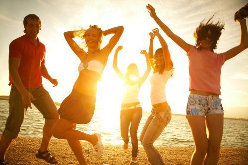 happy young teens dancing at the beach on beautiful summer sunset