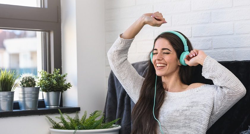 Portrait of beautiful smiling young woman with headphones indoors listening music