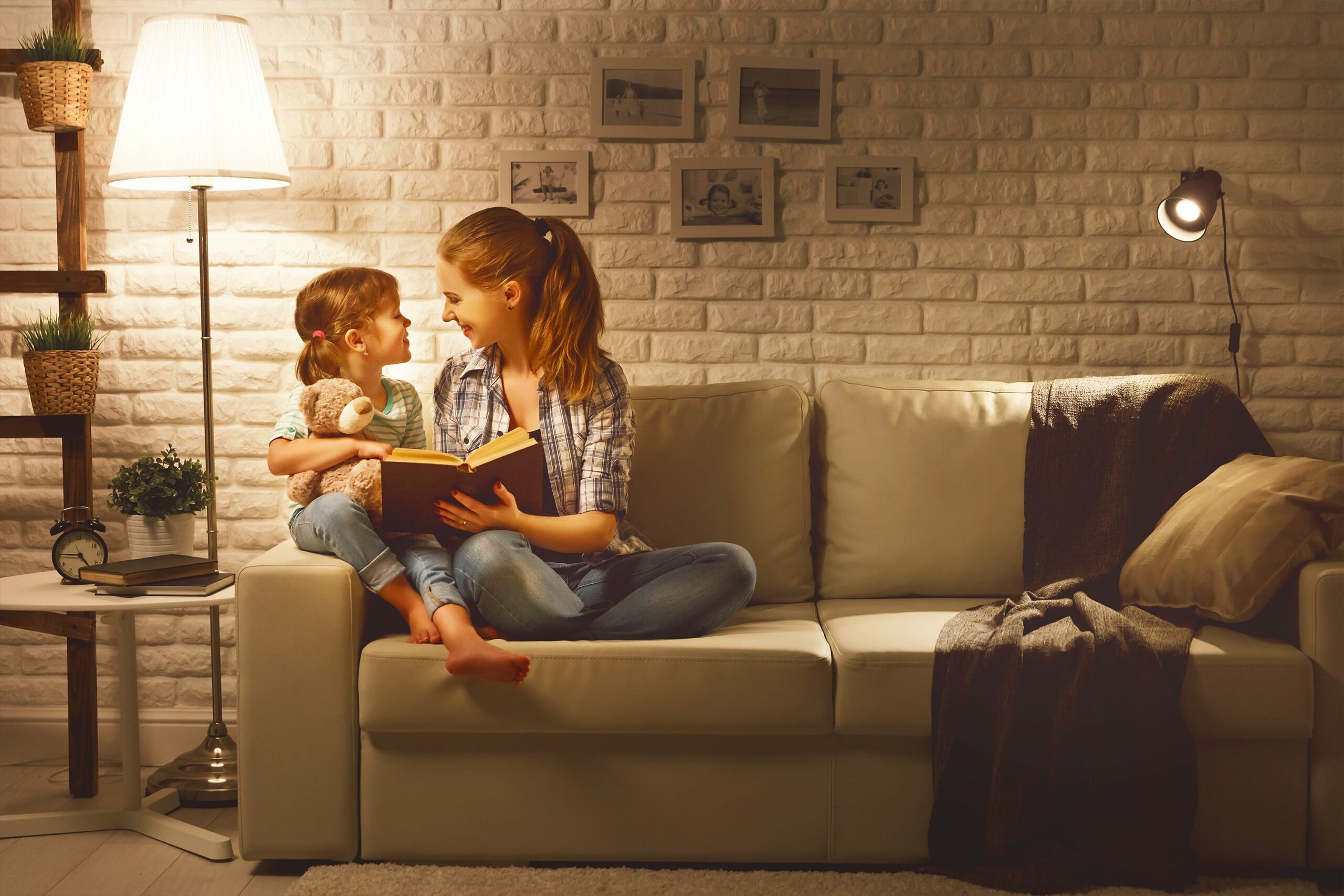 Family before going to bed mother reads to her child daughter book near a lamp in the evening E27
