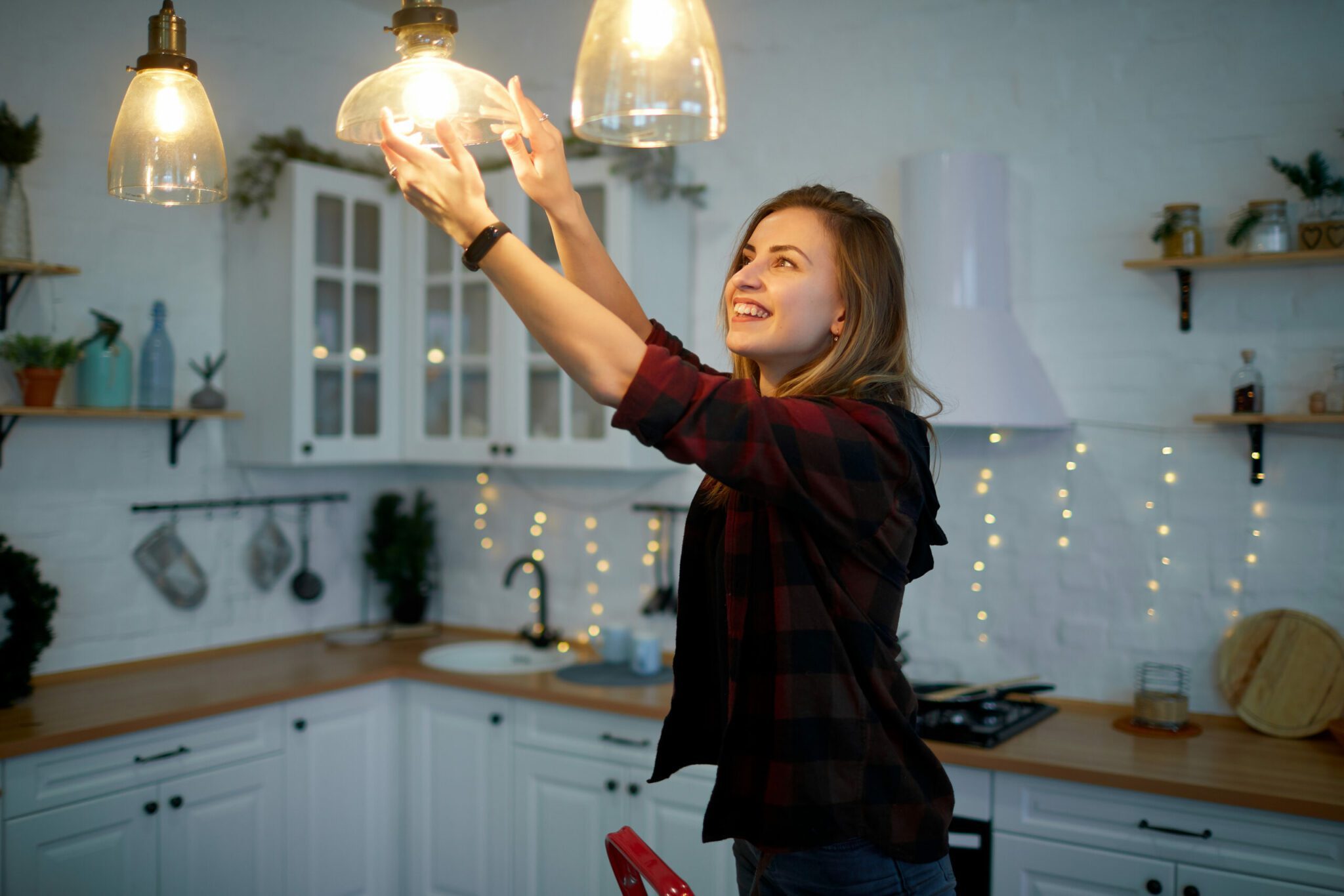 Young happy woman twists a light bulb in the kitchen lamp Naturalna