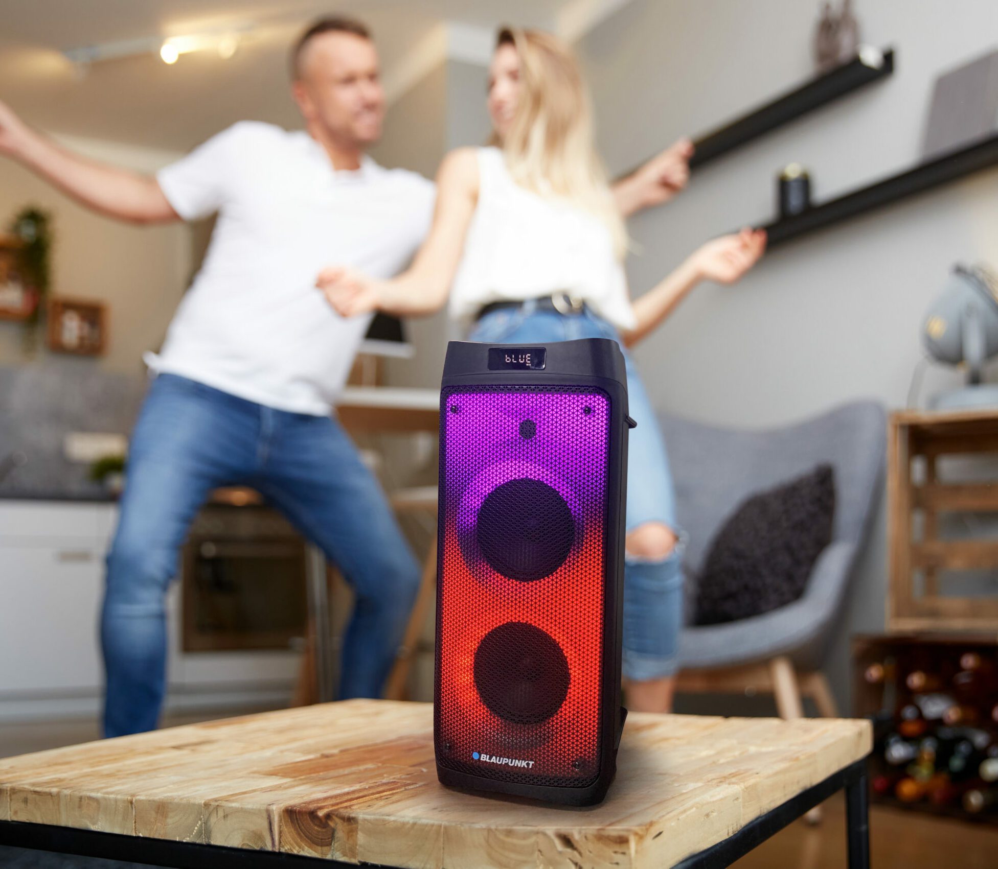 Close Up,Of,Smart,Speaker,On,Wooden,Table,Against,Happy,Couple